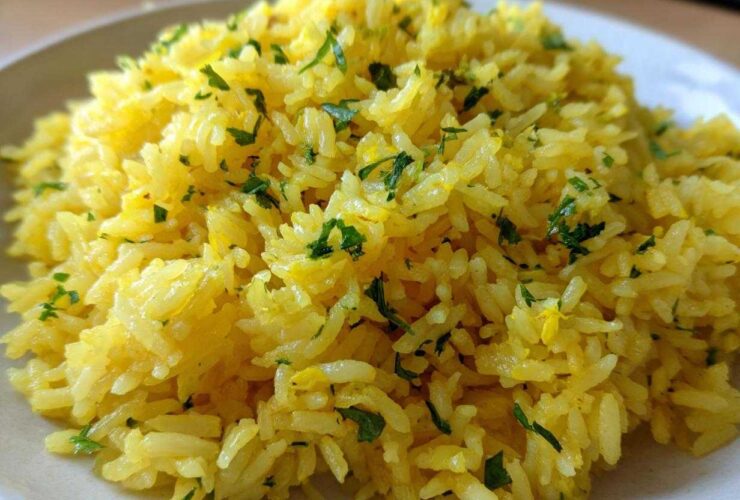 Close-up of fluffy, bright yellow mediterranean rice seasoned and topped with chopped fresh parsley.