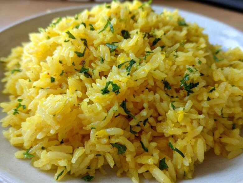 Close-up of fluffy, bright yellow mediterranean rice seasoned and topped with chopped fresh parsley.