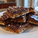 A stack of rich caramel ritz cracker christmas cookies topped with melted chocolate and sea salt.