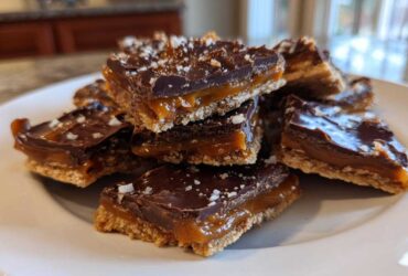 A stack of rich caramel ritz cracker christmas cookies topped with melted chocolate and sea salt.