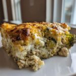 A close-up slice of creamy chicken broccoli rice casserole topped with melted, browned cheese.