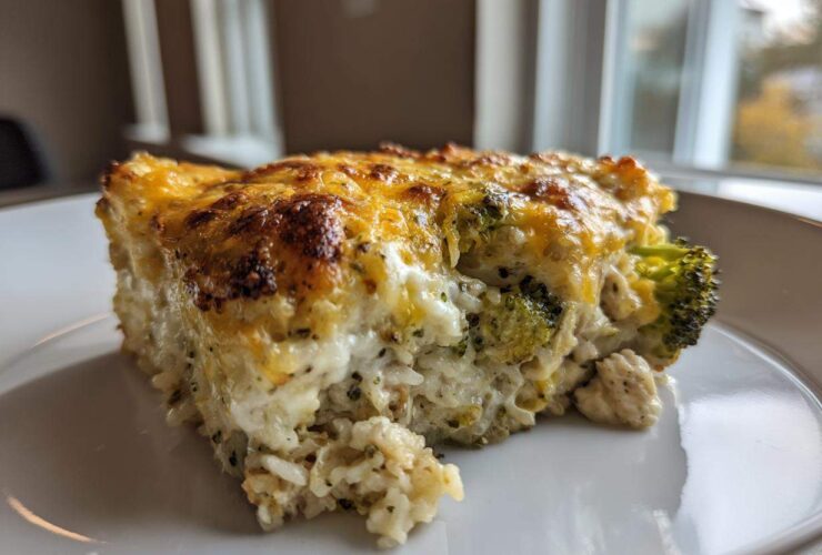 A close-up slice of creamy chicken broccoli rice casserole topped with melted, browned cheese.