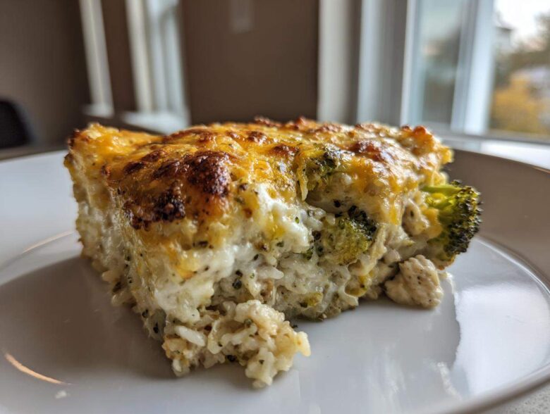 A close-up slice of creamy chicken broccoli rice casserole topped with melted, browned cheese.