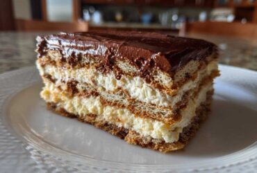 Close-up of a layered slice of chocolate eclair cake with cream filling and chocolate frosting.
