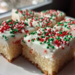 Close-up of frosted Christmas sugar cookie bars topped with red, green, and white sprinkles.