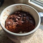 A rich, dark chocolate Cottage Cheese Microwave Brownie topped with chocolate chips, served in a light blue mug.
