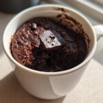 Close-up of a rich, dark chocolate Cottage Cheese Microwave Brownie baked inside a white mug.