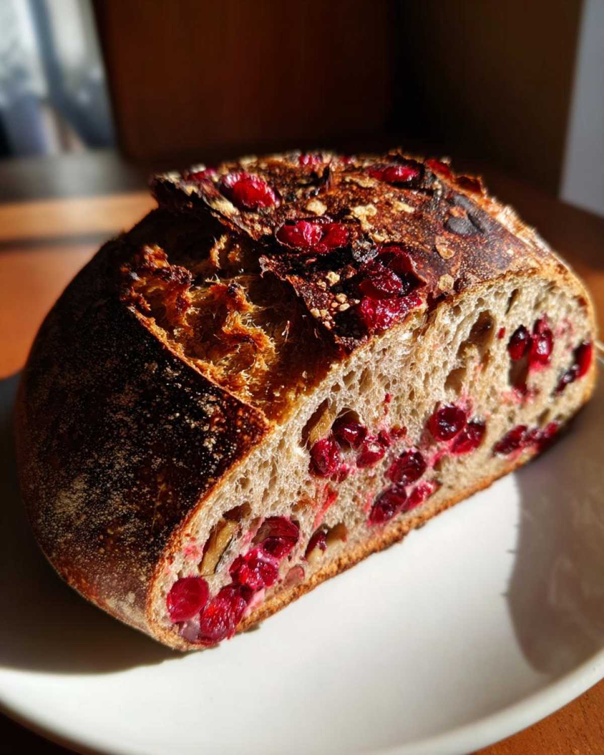 Close-up of a sliced loaf of cranberry walnut bread showing bright red cranberries and walnuts embedded in the crumb.