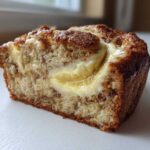 Close-up of a slice of moist cream cheese banana bread showing a rich cream cheese swirl.