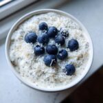 Overhead view of creamy coconut chia pudding topped with shredded coconut and fresh blueberries.