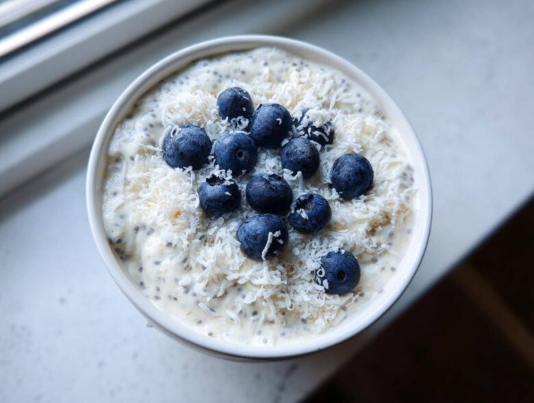 Overhead view of creamy coconut chia pudding topped with shredded coconut and fresh blueberries.