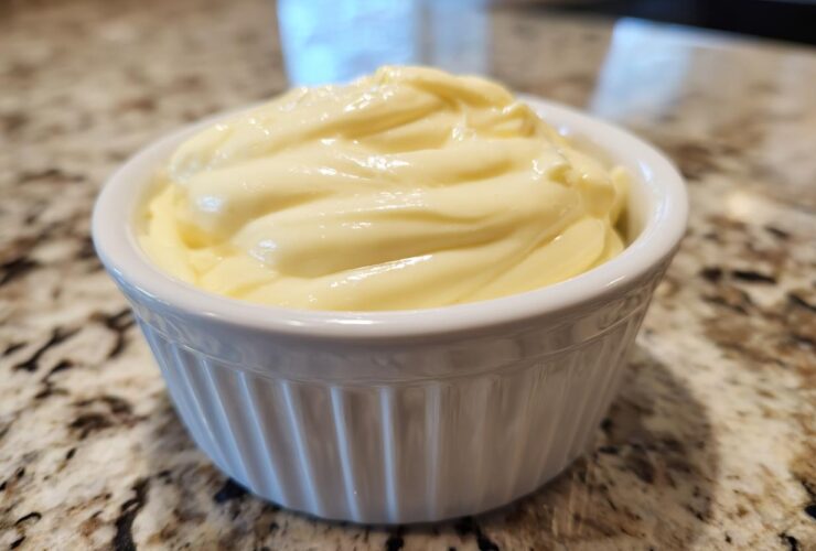 Close-up of rich, creamy garlic aioli swirled high in a small white fluted ramekin.
