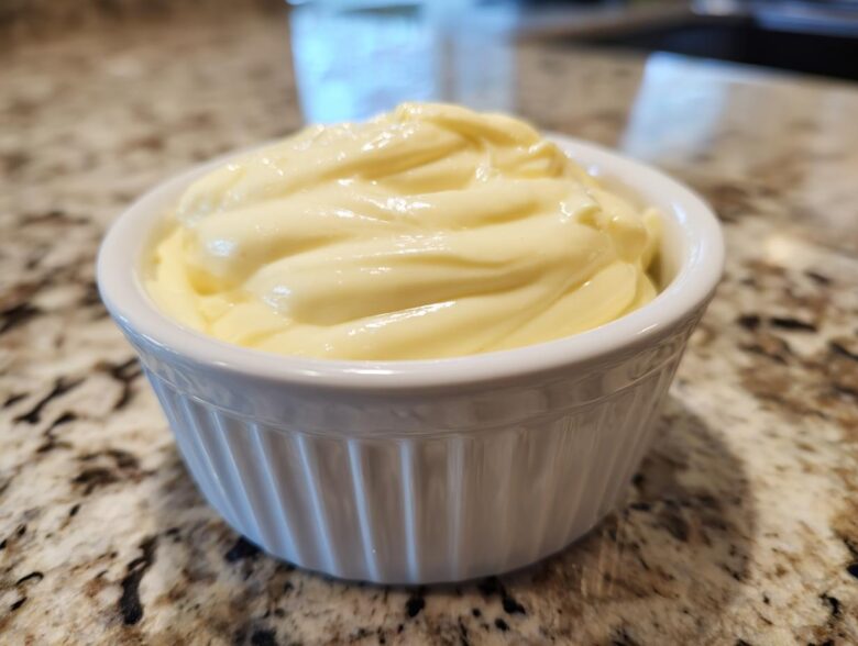 Close-up of rich, creamy garlic aioli swirled high in a small white fluted ramekin.