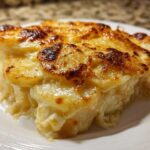 A close-up serving of creamy scalloped potatoes showing layers of tender potatoes and a golden-brown, cheesy top.