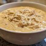 Close-up of a bowl filled with creamy white chicken chili, featuring shredded white chicken.
