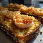Close-up of crispy shrimp toast topped with a perfectly cooked shrimp and golden breadcrumbs.
