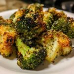 Close-up of perfectly cooked smashed broccoli florets with a crispy, golden-brown, seasoned coating.