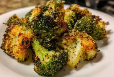 Close-up of perfectly cooked smashed broccoli florets with a crispy, golden-brown, seasoned coating.
