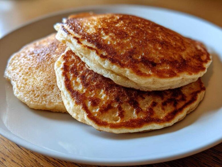 Close-up of two golden-brown almond flour pancakes stacked on a light plate.