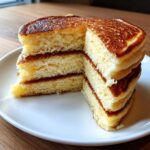 Close-up of a stack of fluffy almond flour pancakes cut to show the light, airy interior texture.