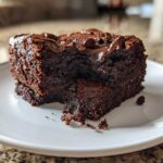 Close-up of a rich, fudgy slice of sweet potato brownies topped with melted chocolate chips on a white plate.