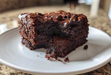 Close-up of a rich, fudgy slice of sweet potato brownies topped with melted chocolate chips on a white plate.