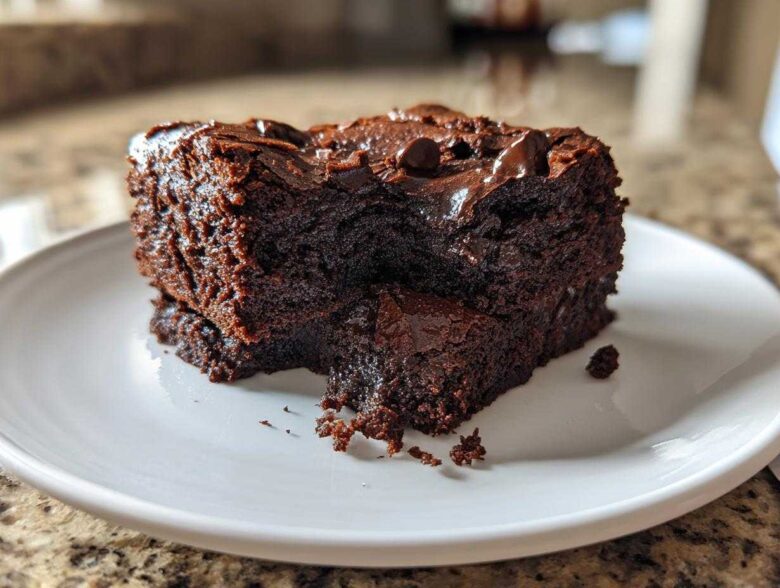 Close-up of a rich, fudgy slice of sweet potato brownies topped with melted chocolate chips on a white plate.