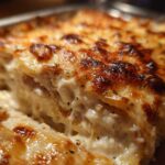 A close-up, macro shot showing a creamy, cheesy slice of Garlic parmesan chicken bake with a browned, bubbly top.