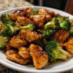 Close-up of glossy, saucy chicken and bright green broccoli florets, a perfect chicken and broccoli dinner.