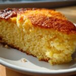 Close-up of a moist, golden slice of skillet cornbread with a dark, caramelized crust.