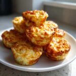 A stack of golden brown, fluffy egg bites piled high on a white plate, ready to eat.