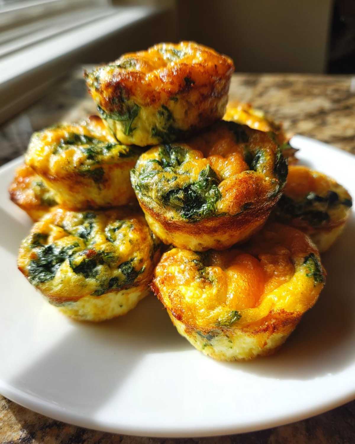 A stack of golden-brown, high-protein egg bites mixed with spinach, ready to eat.