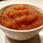 Close-up of chunky, spiced homemade applesauce served in a small white bowl.