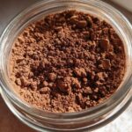 Close-up overhead view of rich brown homemade hot cocoa mix powder stored in a clear glass jar.