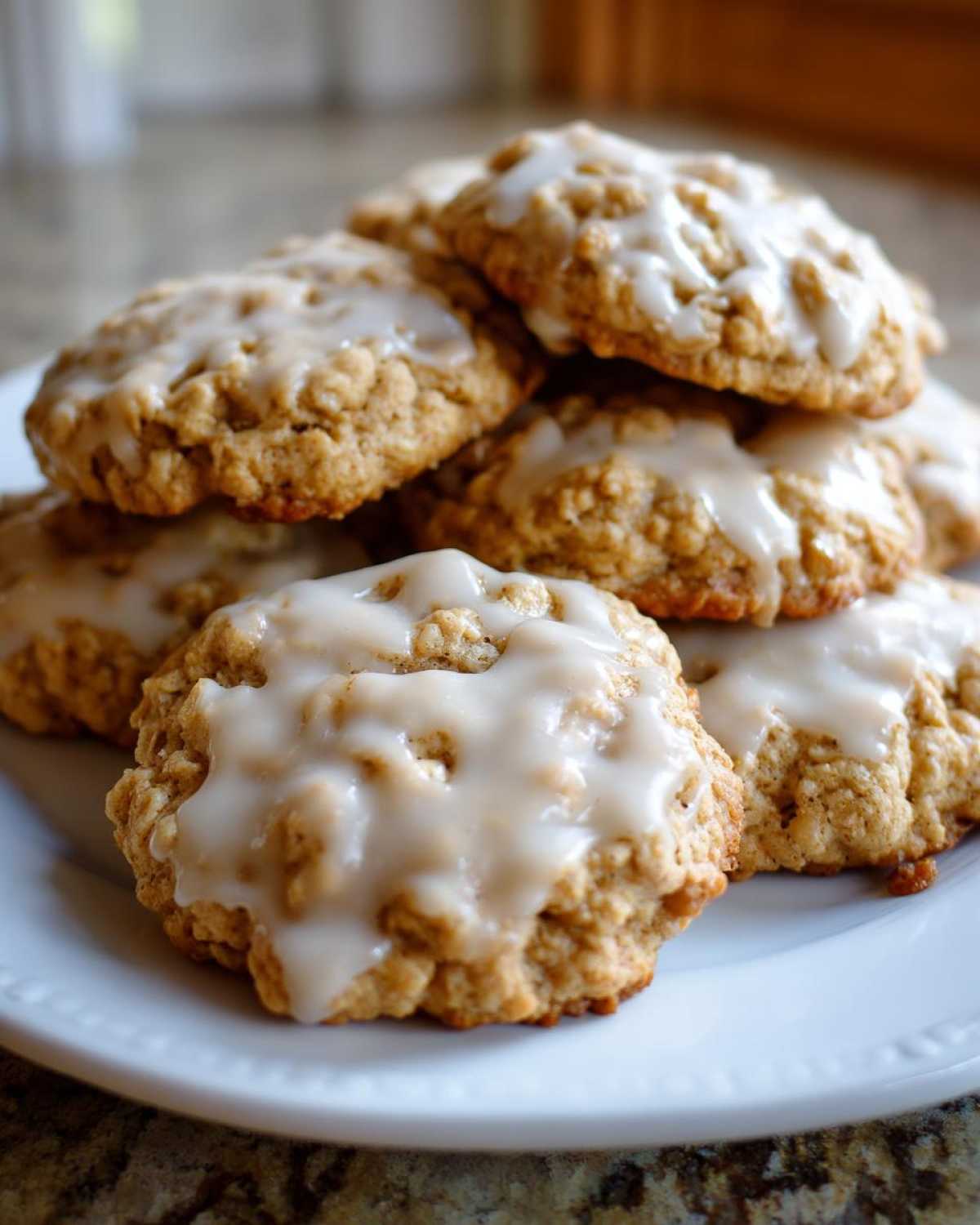 A close-up stack of soft, chewy iced oatmeal cookies drizzled with sweet white glaze.
