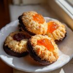 Four Italian butter cookies with a crumbly texture, topped with jam, and dipped in dark chocolate.
