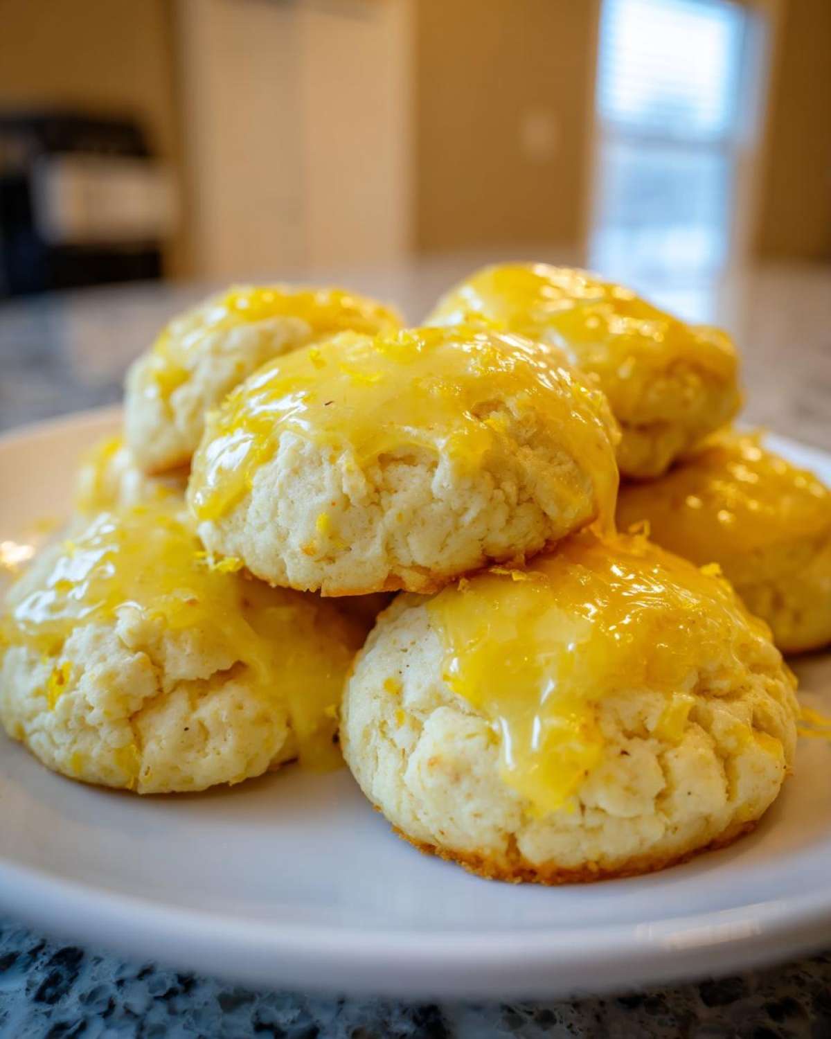 A stack of soft, round Italian ricotta cookies topped with a bright yellow citrus glaze.