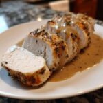 A perfectly cooked and sliced instant pot turkey breast drizzled with savory brown gravy on a white plate.