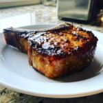 Close-up of a thick, bone-in pork chop cooked to perfection using a flavorful marinade for pork chops.