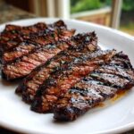 Close-up of perfectly grilled steak slices showing a medium-rare center, seasoned with herbs from the carne asada marinade.