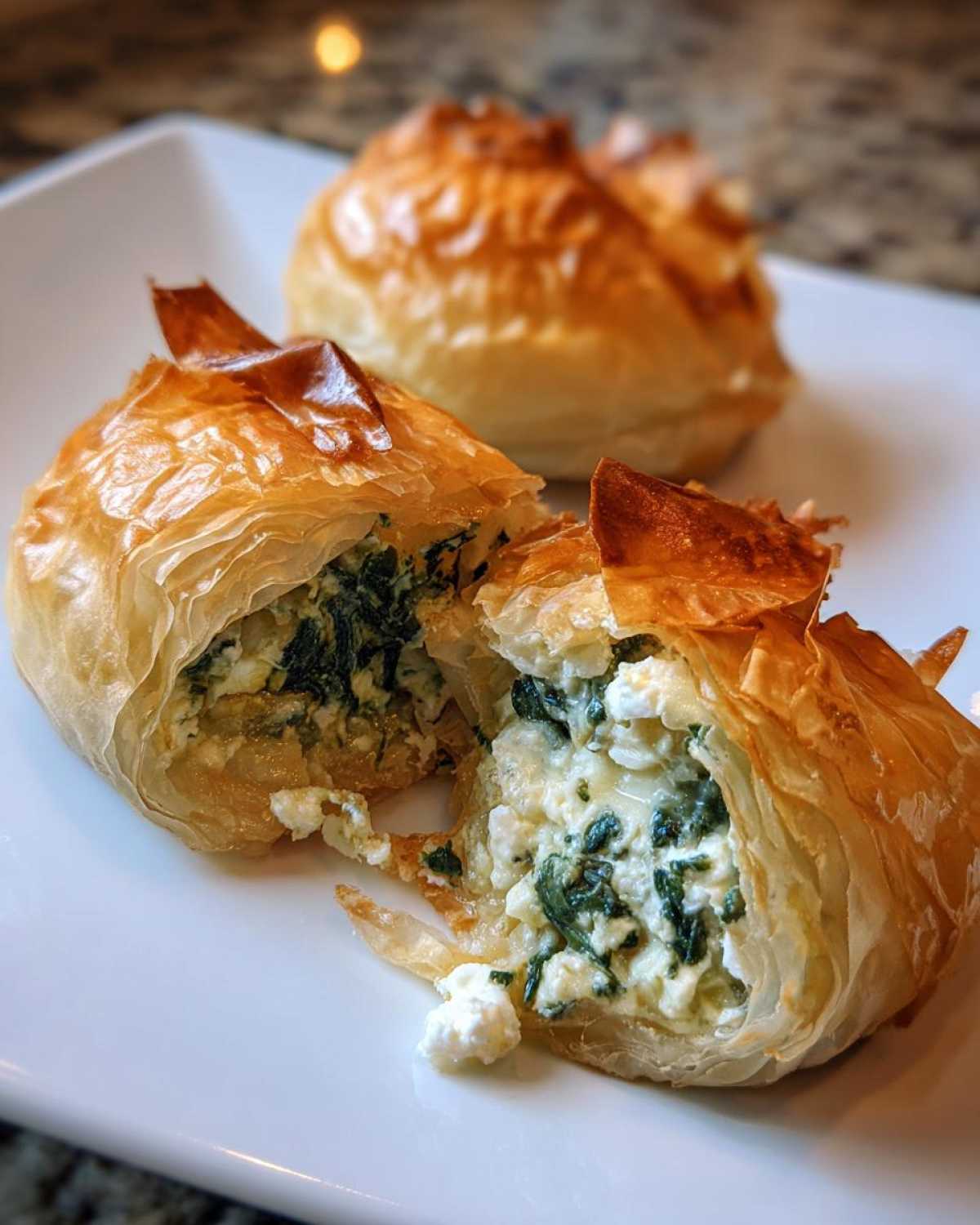 Close-up of a Mediterranean Spinach and Feta Cheese Crisp cut open, showing flaky phyllo dough and creamy filling.