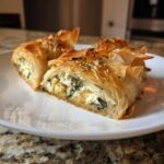 Close-up of flaky Mediterranean Spinach and Feta Cheese Crisps slices filled with white cheese and green spinach.