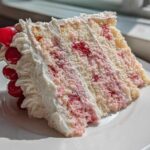 A tall, moist slice of 3-layer cherry cake featuring white cake, pink cherry filling, and whipped cream frosting, garnished with maraschino cherries.