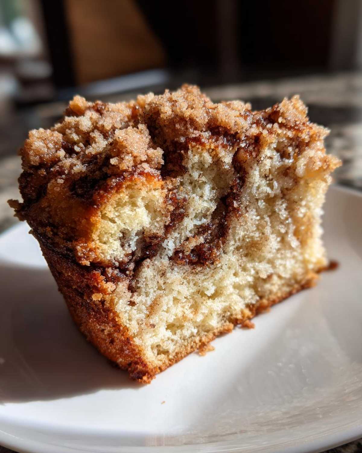 Close-up of a moist slice of coffee cake showing the tender crumb and thick cinnamon streusel topping.