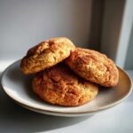 Three soft, thick pumpkin snickerdoodle cookies generously coated in cinnamon sugar, stacked on a small ceramic plate.