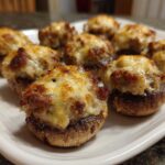 Close-up of several baked sausage stuffed mushrooms topped with golden, melted cheese, ready to serve.