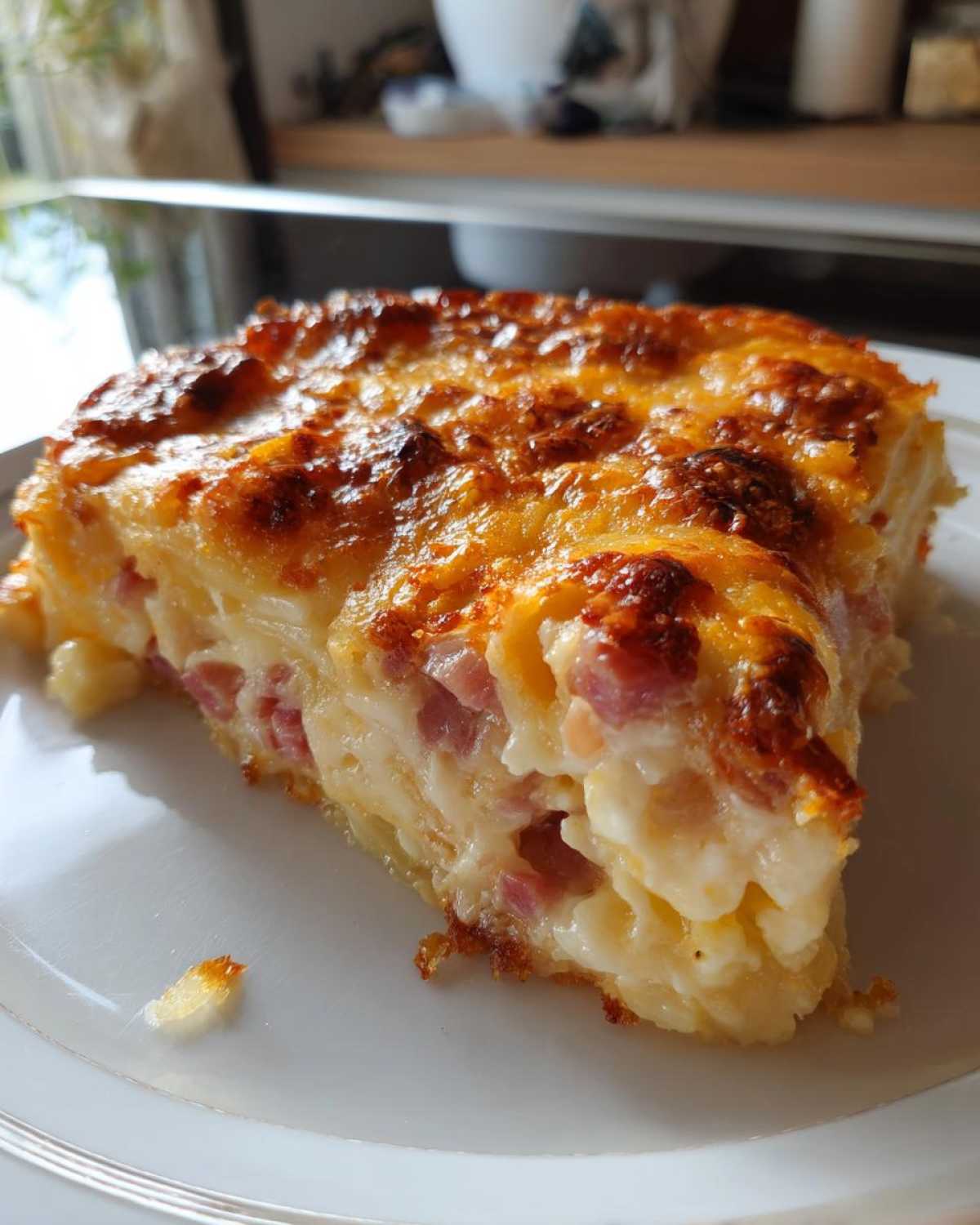 A thick, golden-brown slice of scalloped potatoes and ham bake with a creamy sauce and bubbly cheese topping.