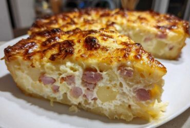 A thick slice of scalloped potatoes and ham bake with a bubbly, browned cheese crust, served on a white plate.