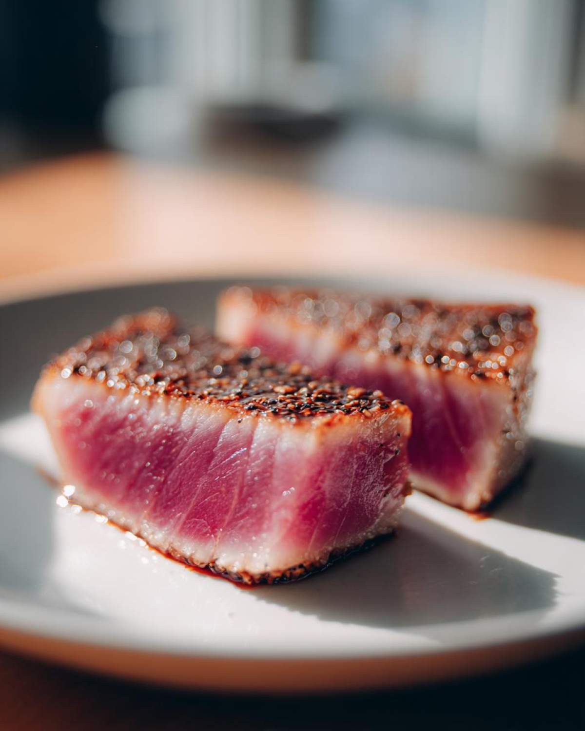 Two thick slices of perfectly seared tuna steak, showing a bright pink rare center and a dark, pepper-crusted edge, ready after using the MARINADE FOR TUNA STEAK.