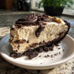 A generous slice of creamy, no-bake ice cream pie with an Oreo crust and cookie topping.